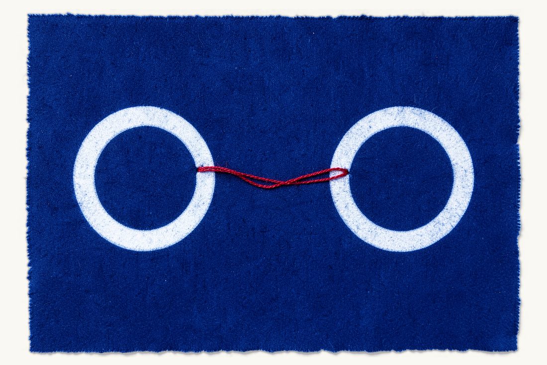 Divorce in Türkiye for foreigners and binational couples: two plain wedding rings drifting apart, the red thread between them broken into two loose ends, cyanotype print