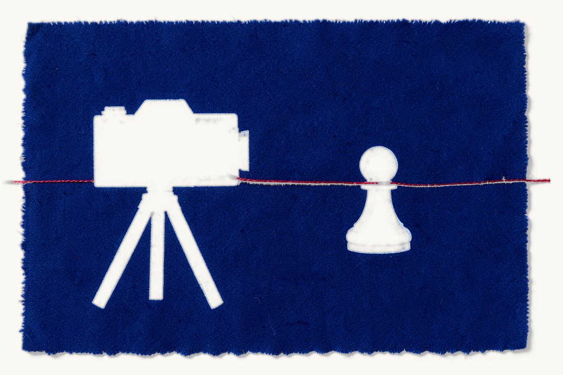 An athlete's image rights in commercial deals: a large old camera on a tripod aimed at a white chess pawn standing on a football, joined to it by a red thread, cyanotype print